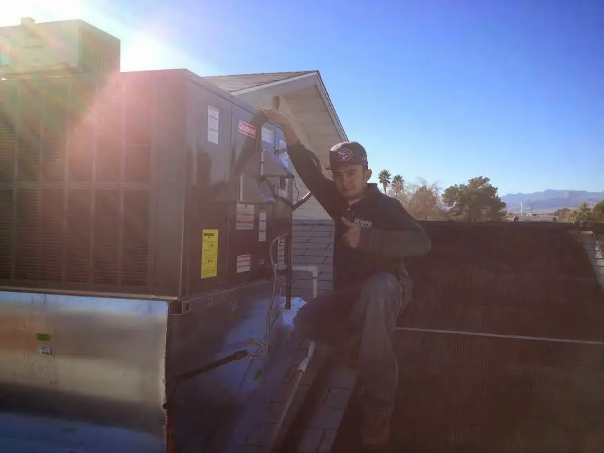 HVAC technician performing Heat Pump Repair on a rooftop unit in Orem